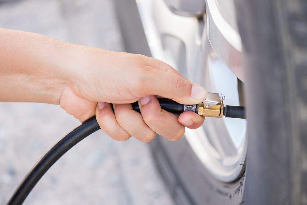 Person putting air in their car tyre.