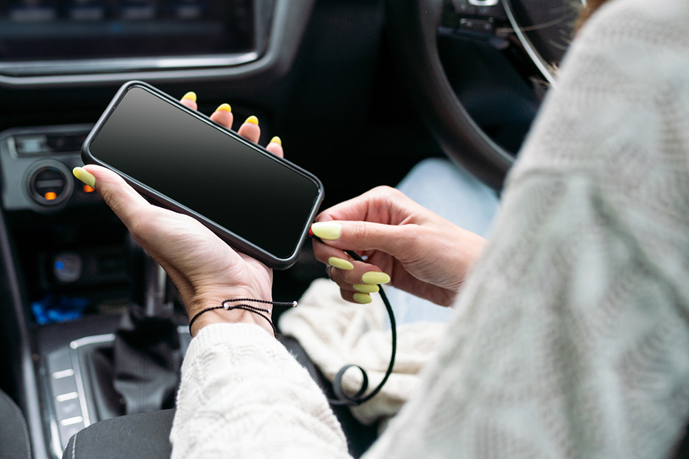 Woman connecting mobile phone to car.