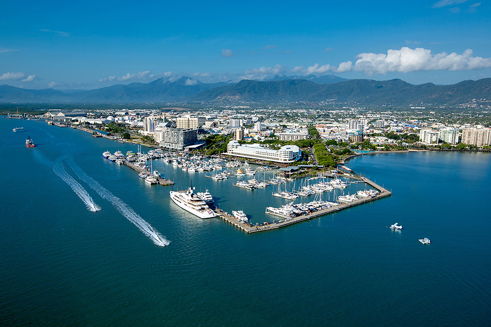 Aerial view of Cairns Marina with boats, Shangri-La hotel and city skyline backed by mountains in Tropical North Queensland