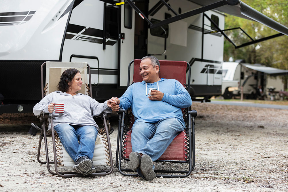 Caravanning couple relaxing at campsite.