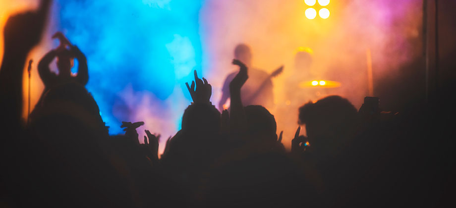 Cheering crowd at concert in front of bright coloured lights